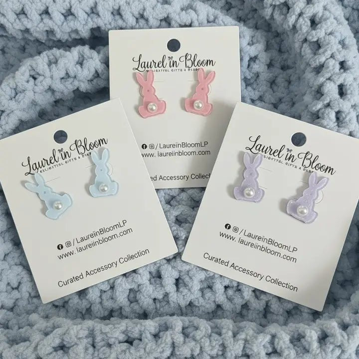 Three pairs of earrings on 'Laurel in Bloom' cards against a textured gray background