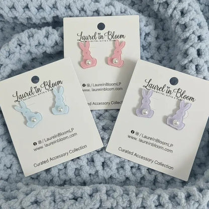 Three pairs of earrings on 'Laurel in Bloom' cards against a textured gray background