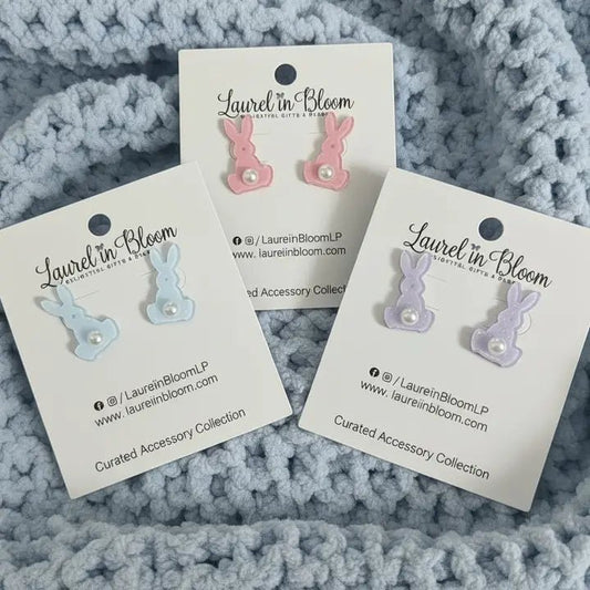Three pairs of earrings on 'Laurel in Bloom' cards against a textured gray background