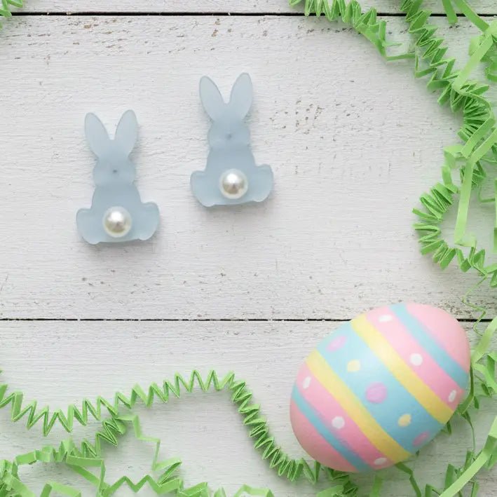 Easter-themed earrings with a decorative egg on a wooden surface.