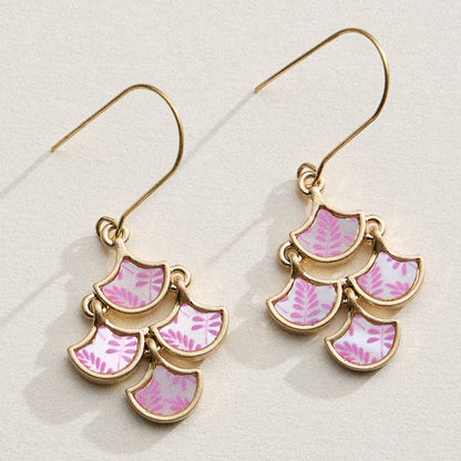 Pair of gold earrings with pink leaf patterns on a light background