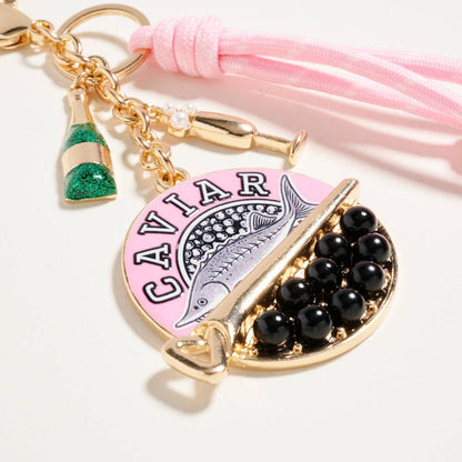 Keychain with 'Caviar' design and black beads on a pink tassel background