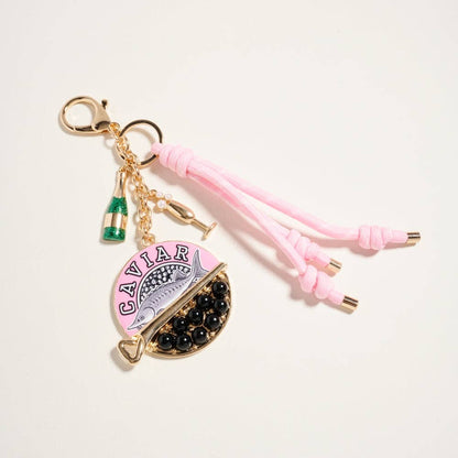 Keychain with pink tassels and 'Caviar' text on a light background