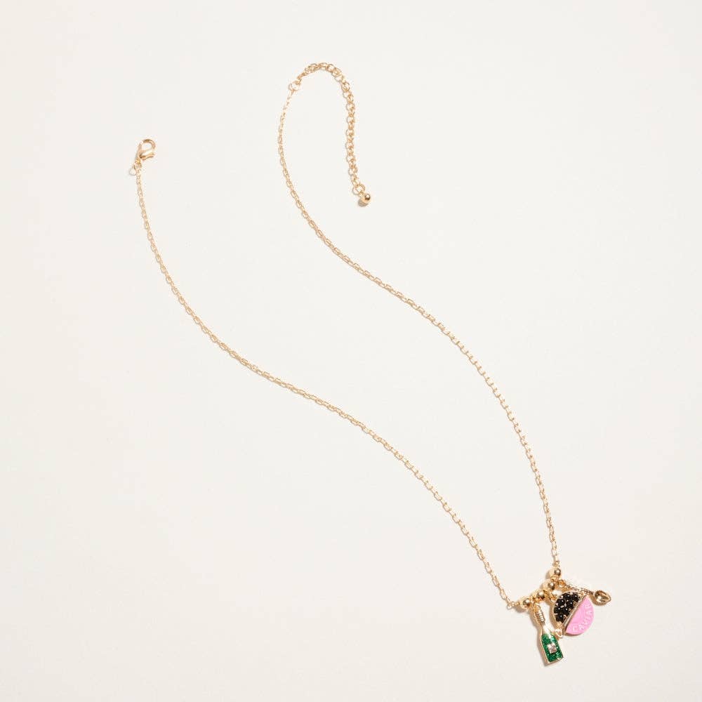 Detailed view of 18k gold dipped caviar tin and champagne bottle charms with intricate enamel and glitter inlays