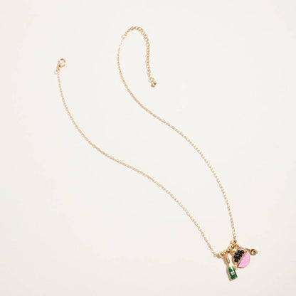 Detailed view of 18k gold dipped caviar tin and champagne bottle charms with intricate enamel and glitter inlays