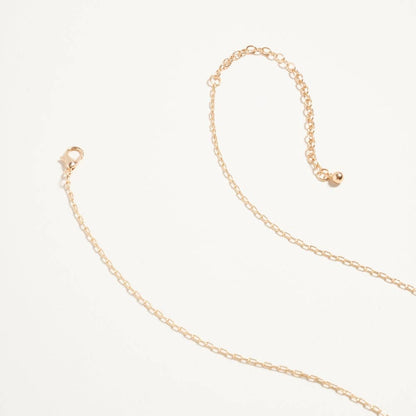 Gold chain necklace on a light beige background