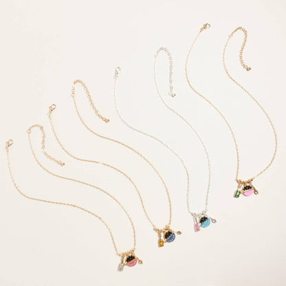 Gold plated caviar and champagne charm necklace with pink glitter accents and miniature spoon pendant on white background