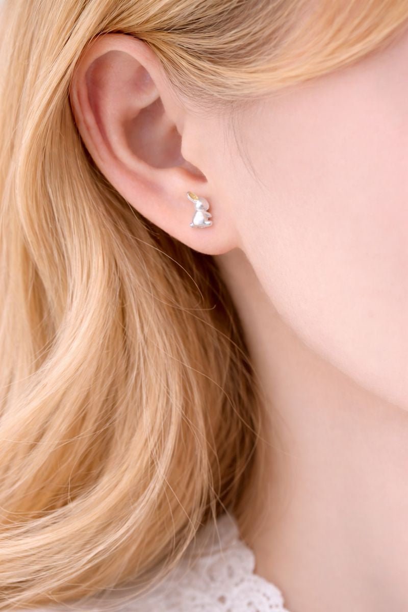 Close-up of an ear wearing a small earring with blonde hair.