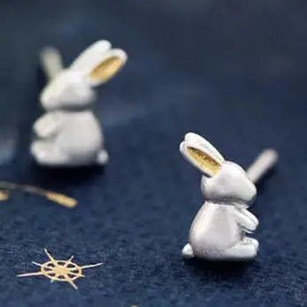 Silver rabbit-shaped earrings on a dark surface