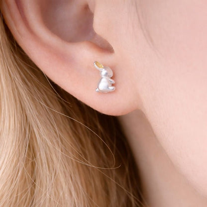 Silver bunny-shaped earring worn by a person with blonde hair.