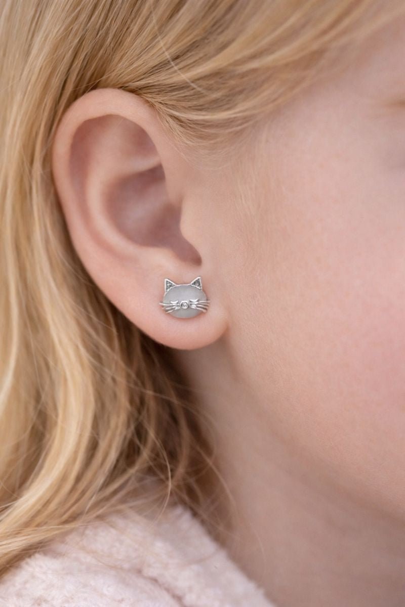 Cat-shaped earrings worn by a person with blonde hair.