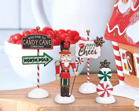 Decorative Christmas items including a nutcracker, candy cane signs, and a gingerbread house on a table.