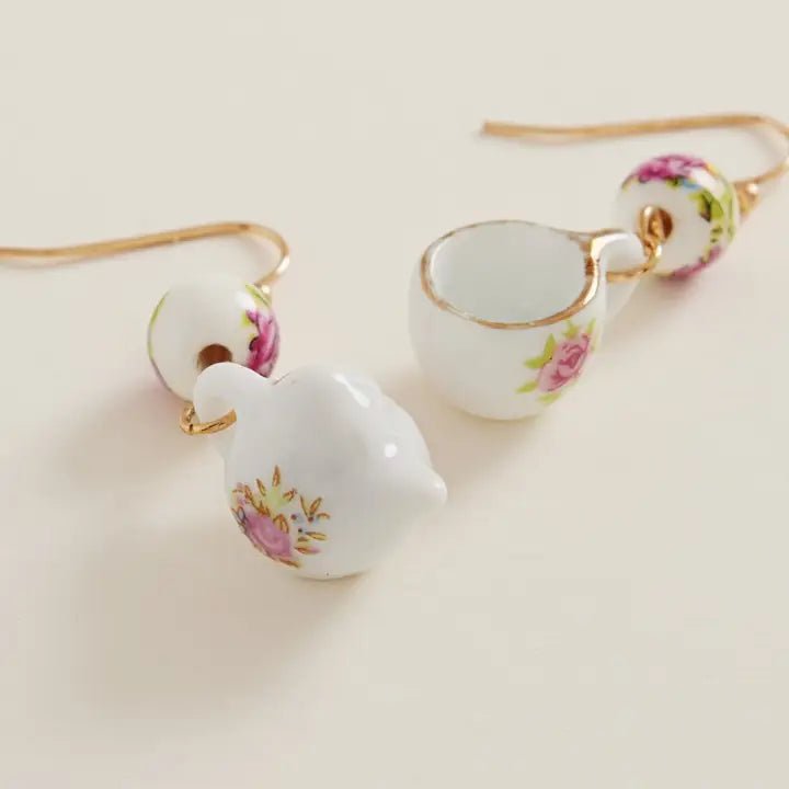 Teacup-shaped earrings with floral designs on a light background