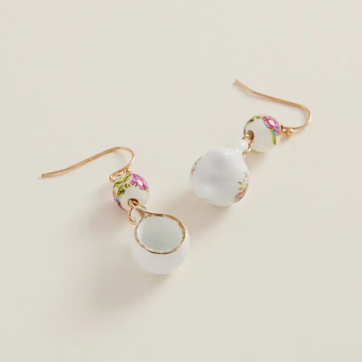 Pair of earrings with white beads and floral designs on a beige background