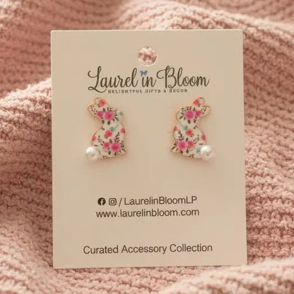 Floral cat-shaped earrings on a 'Laurel in Bloom' card against a pink textured background