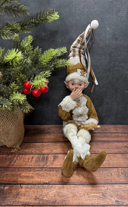 Elf figurine sitting on a wooden surface with a dark background and Christmas tree holding a rolling pin