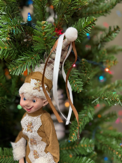 Decorative elf  sitting in a Christmas tree with colorful lights in the background