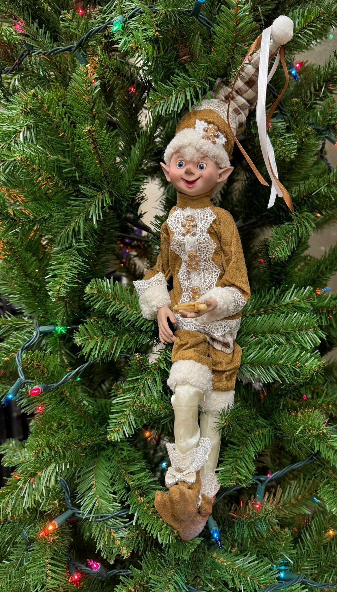 Elf ornament on a decorated Christmas tree with lights and ornaments
