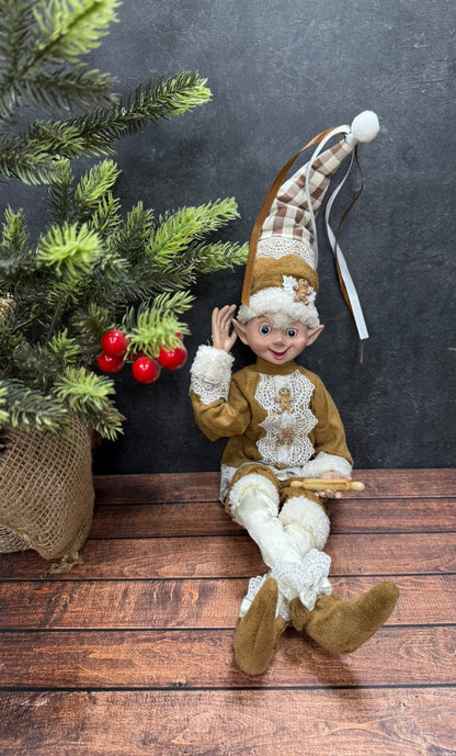 Elf figurine sitting on a wooden surface with a dark background and Christmas decorations.
