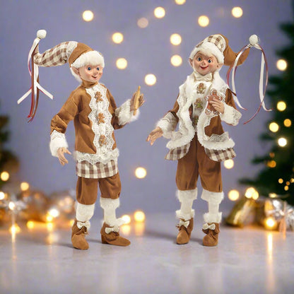 Two Christmas-themed figurines in festive attire against a blurred holiday background with lights.