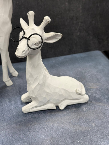White Giraffe figurine wearing black glasses on a gray surface