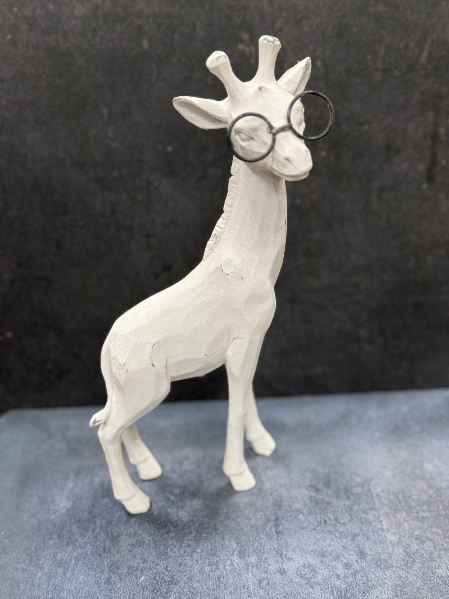 White giraffe figurine wearing glasses on a dark background