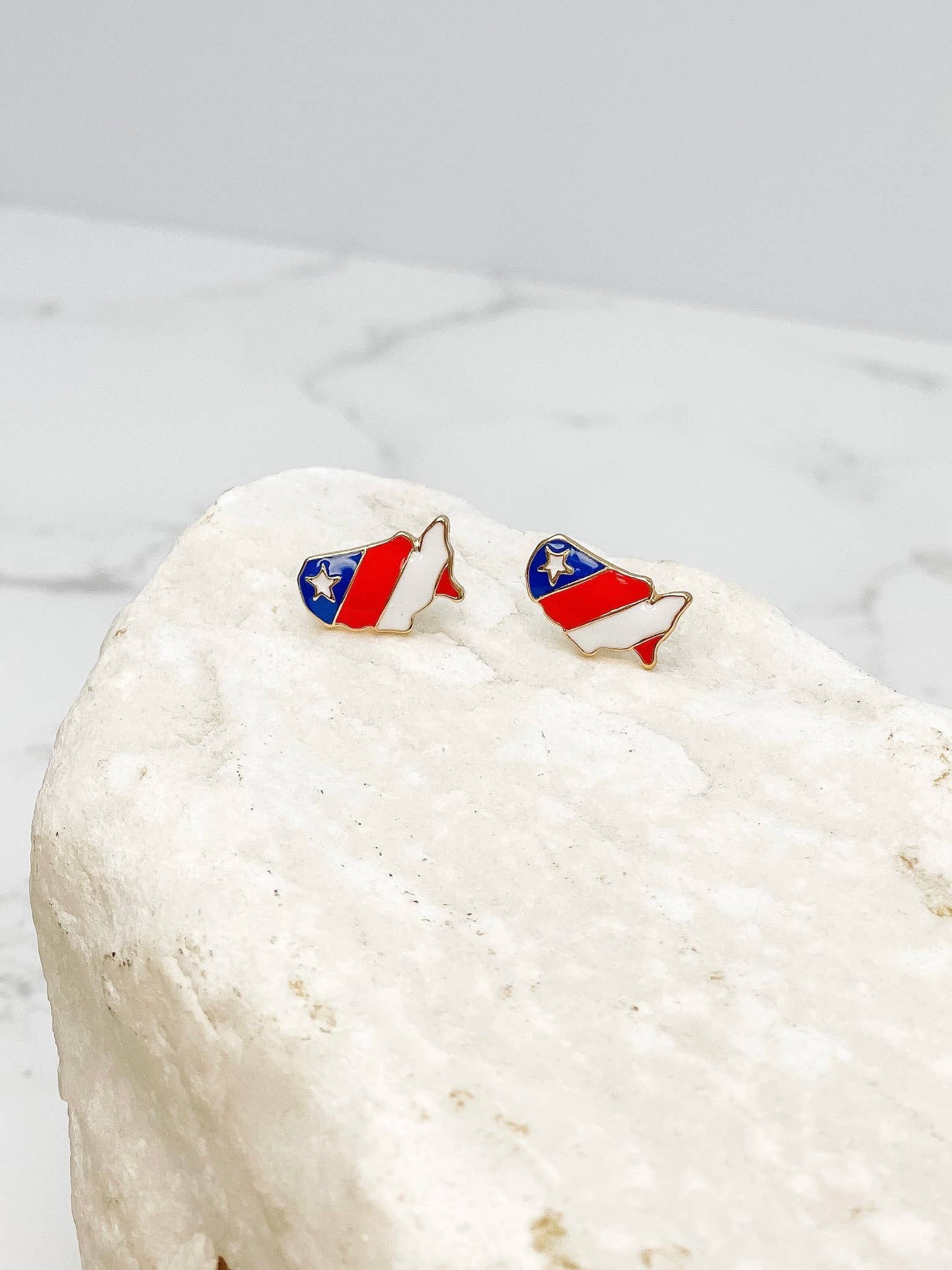 Pair of earrings with a design resembling a flag on a white stone surface