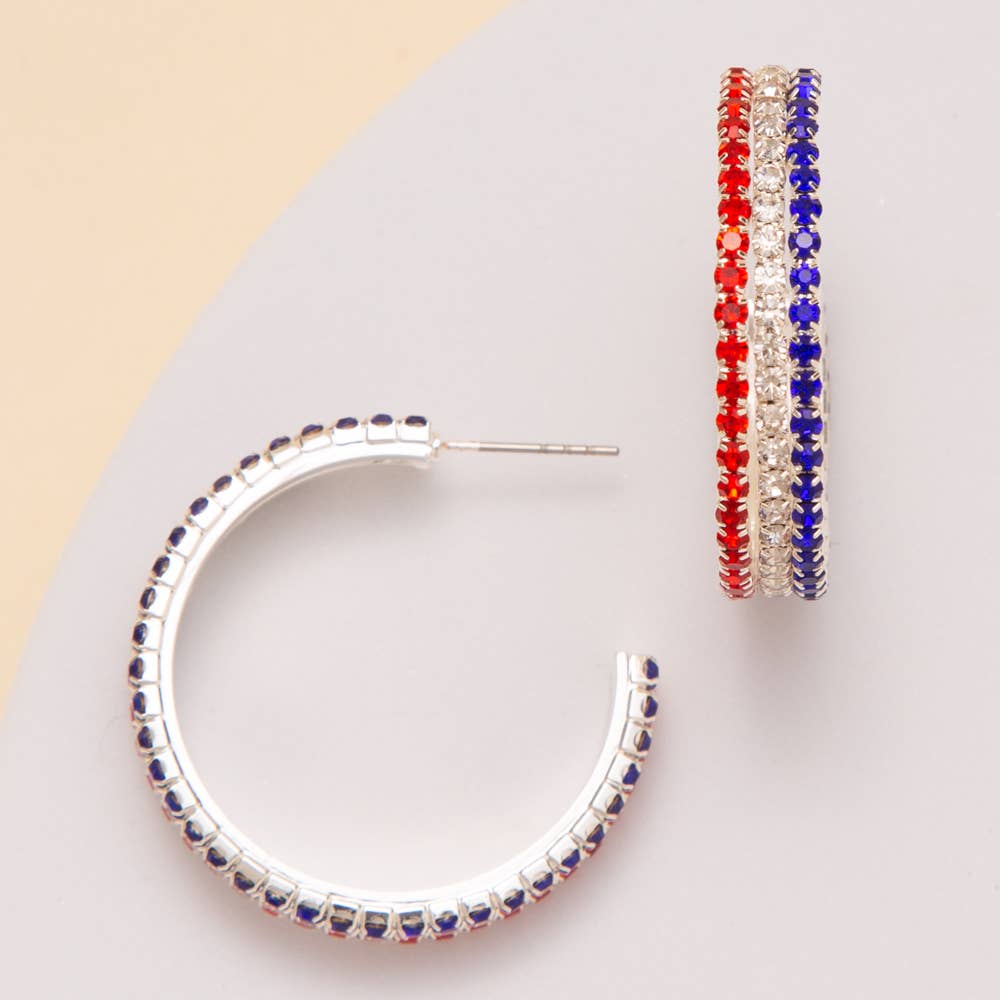 Silver hoop earrings with multicolored gemstones on a light gray background
