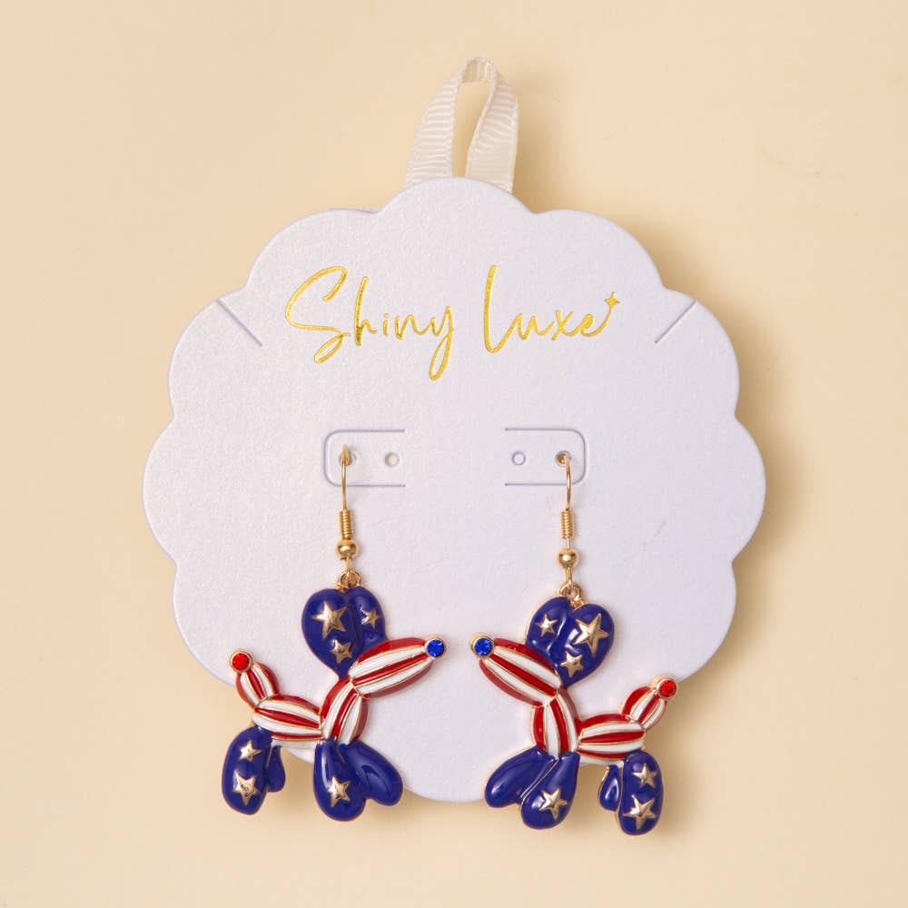 Pair of earrings shaped like balloon dogs on a 'Shiny Luxe' branded card against a beige background