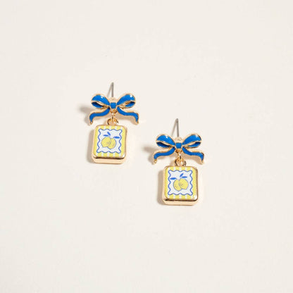 Pair of earrings with blue bows and square designs on a light gray background