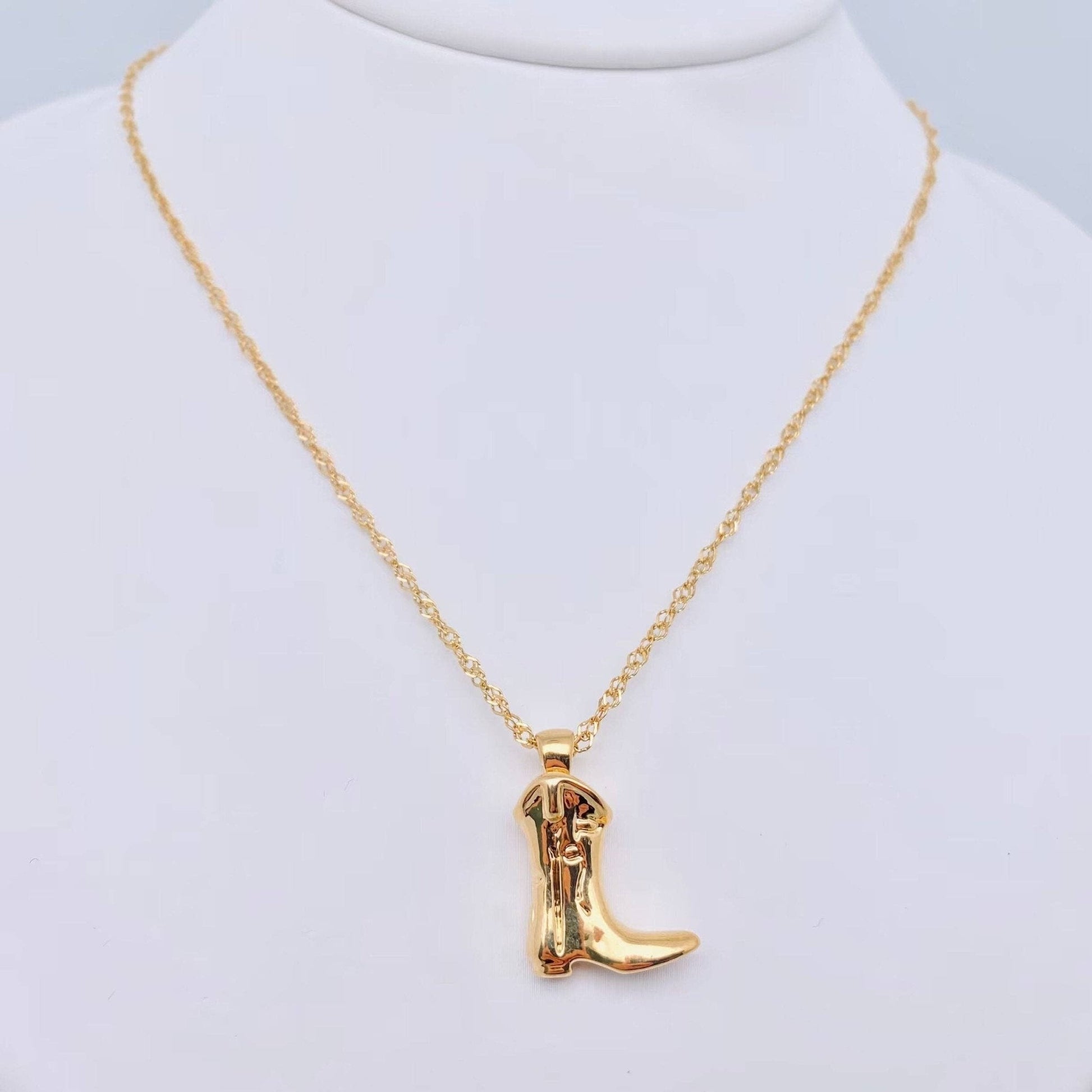 Gold cowboy boot necklace on a mannequin with a white background
