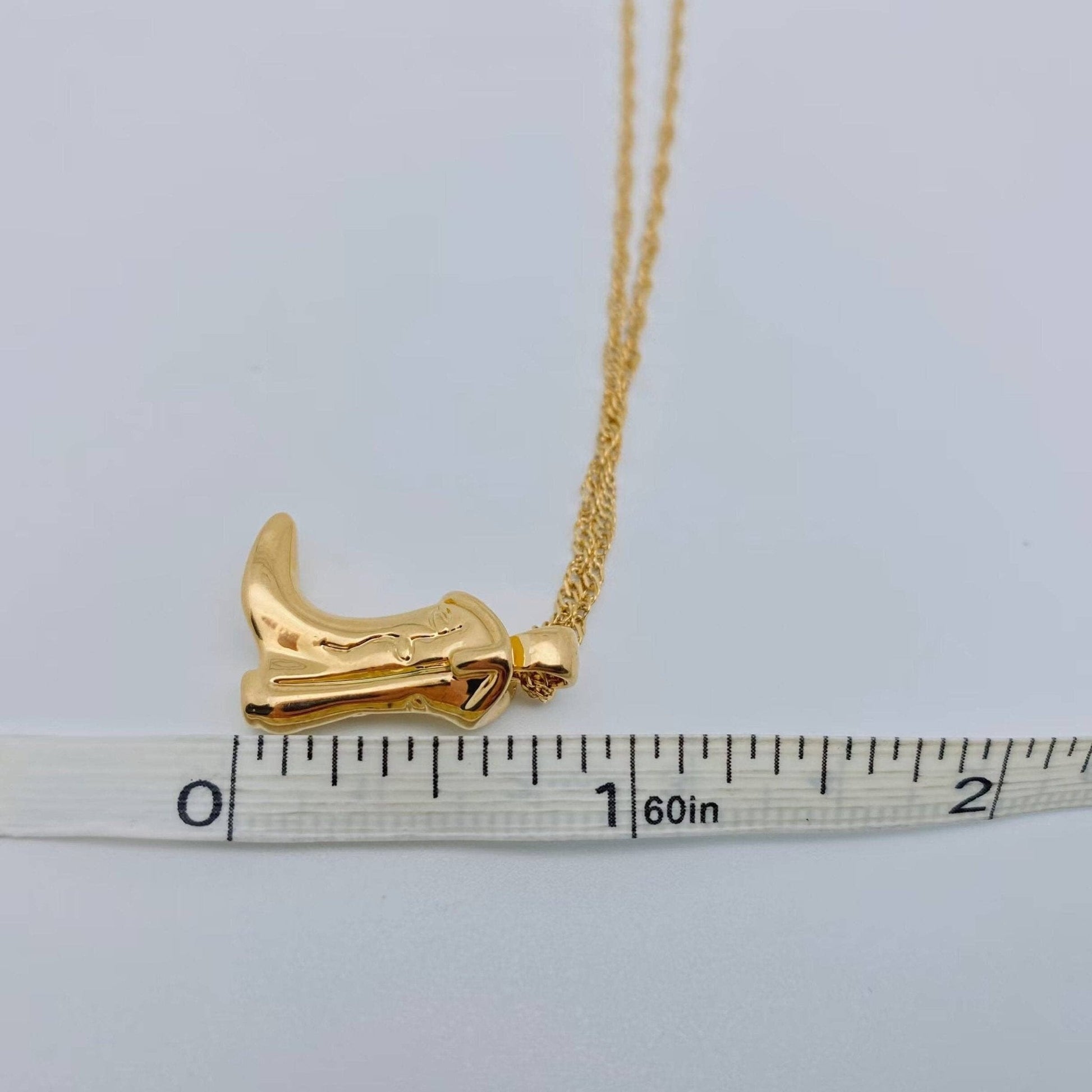 Gold necklace with a unique pendant on a white background with a ruler for scale.