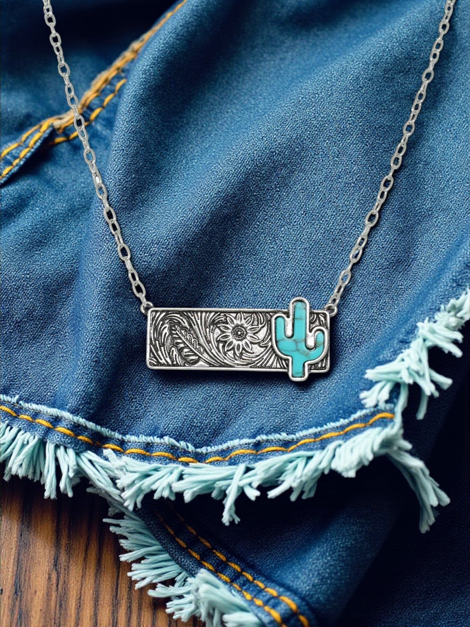 Necklace with a turquoise cactus pendant on a denim background